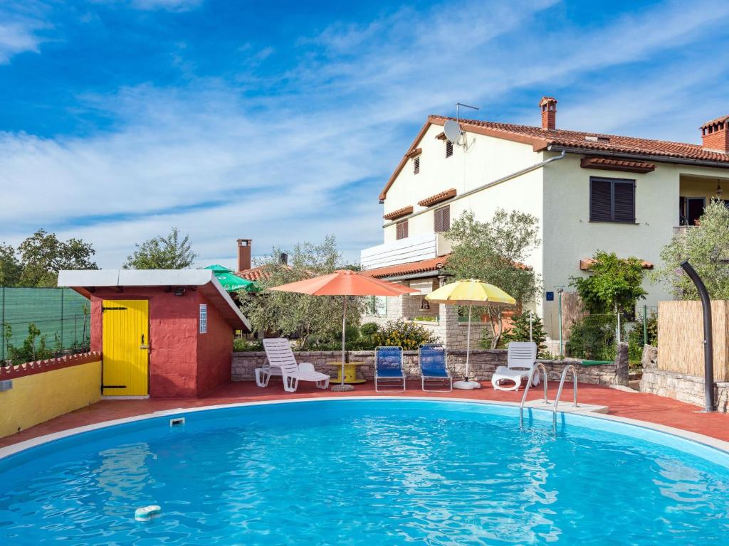 a pool with chairs and umbrellas next to a house at Apartment Pina - PZN317 by Interhome in Tinjan