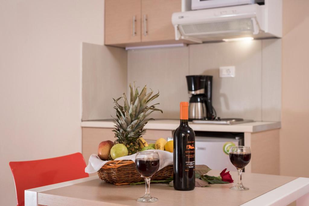 a table with two glasses of wine and a basket of fruit at Atrion Resort Hotel in Agia Marina Nea Kydonias
