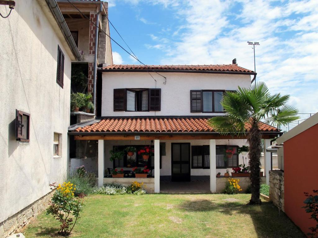 a white house with a palm tree in the yard at Holiday Home Luiza - PRC162 by Interhome in Vabriga