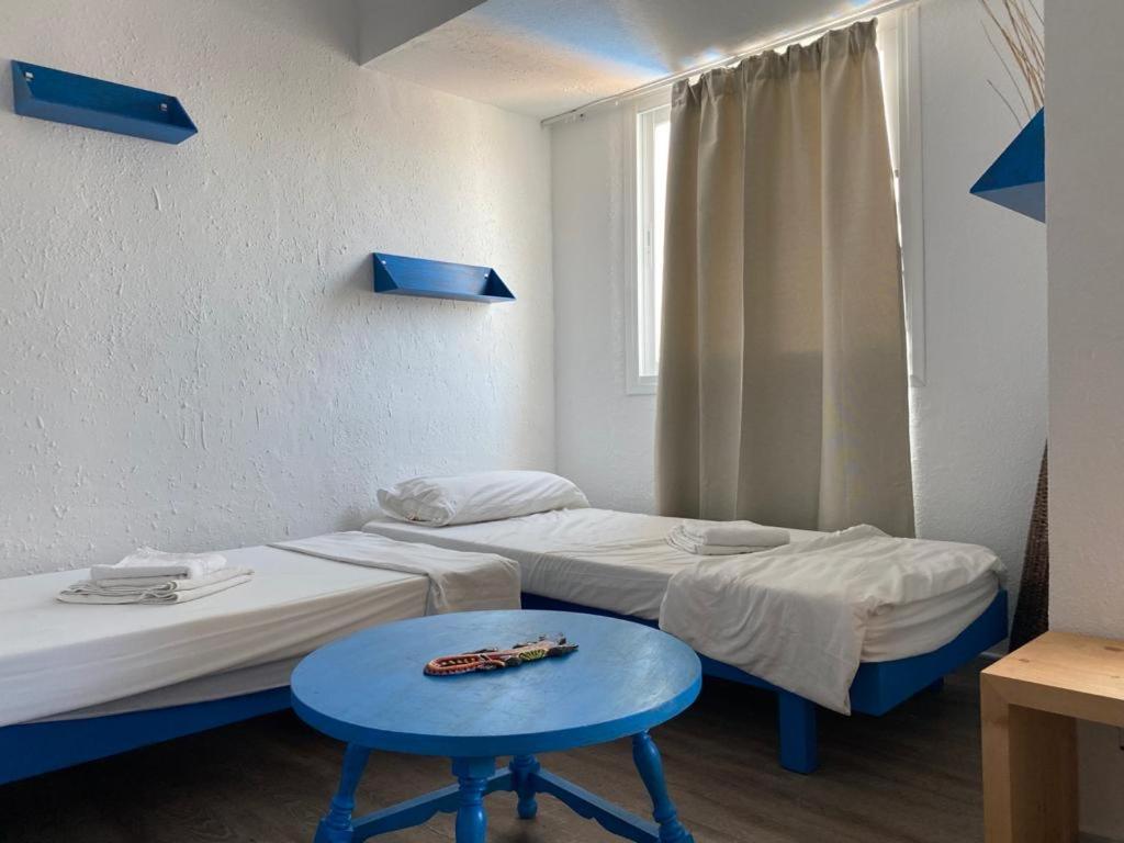 2 letti in una camera con tavolo blu di Gecko Blue, Es Pujols ET - 75 PL a Es Pujols