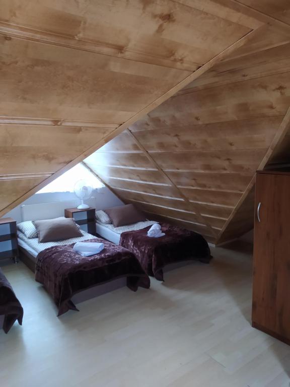a attic room with two beds and a wooden ceiling at Pokoje gościnne LUSIA in Łeba