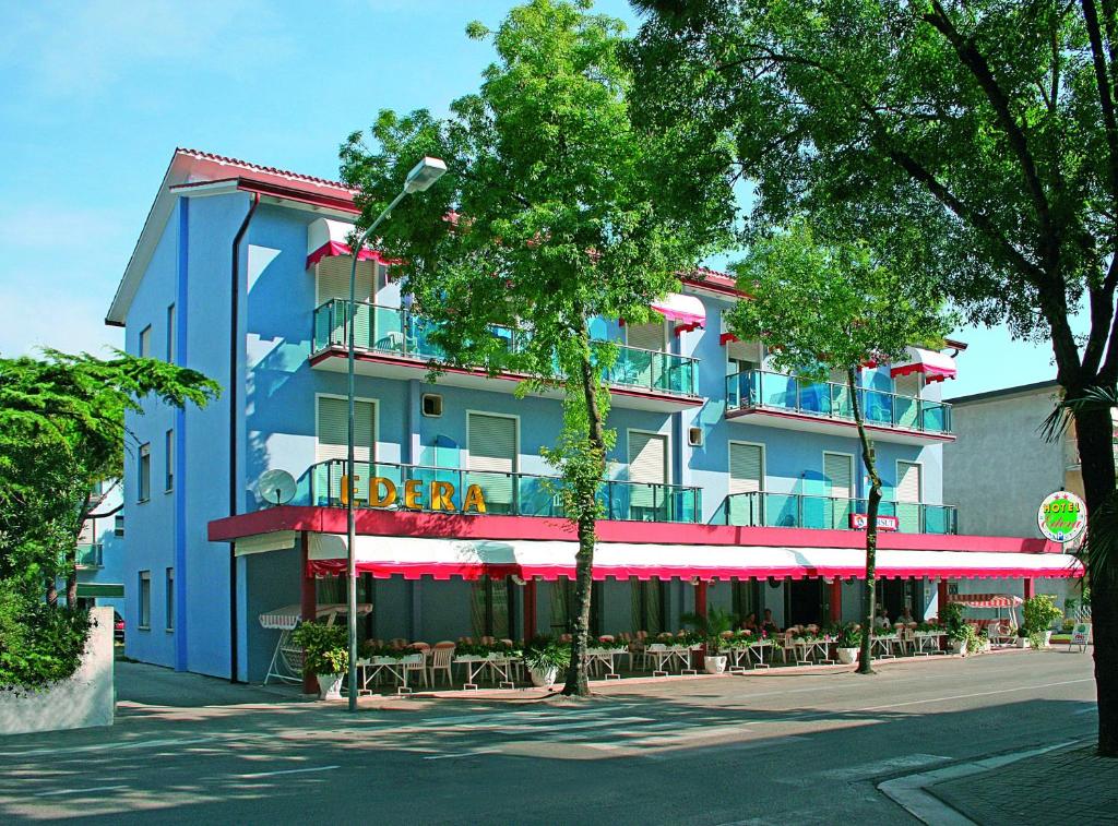 un edificio azul con mesas y sillas delante de él en Hotel Edera, en Lido di Jesolo