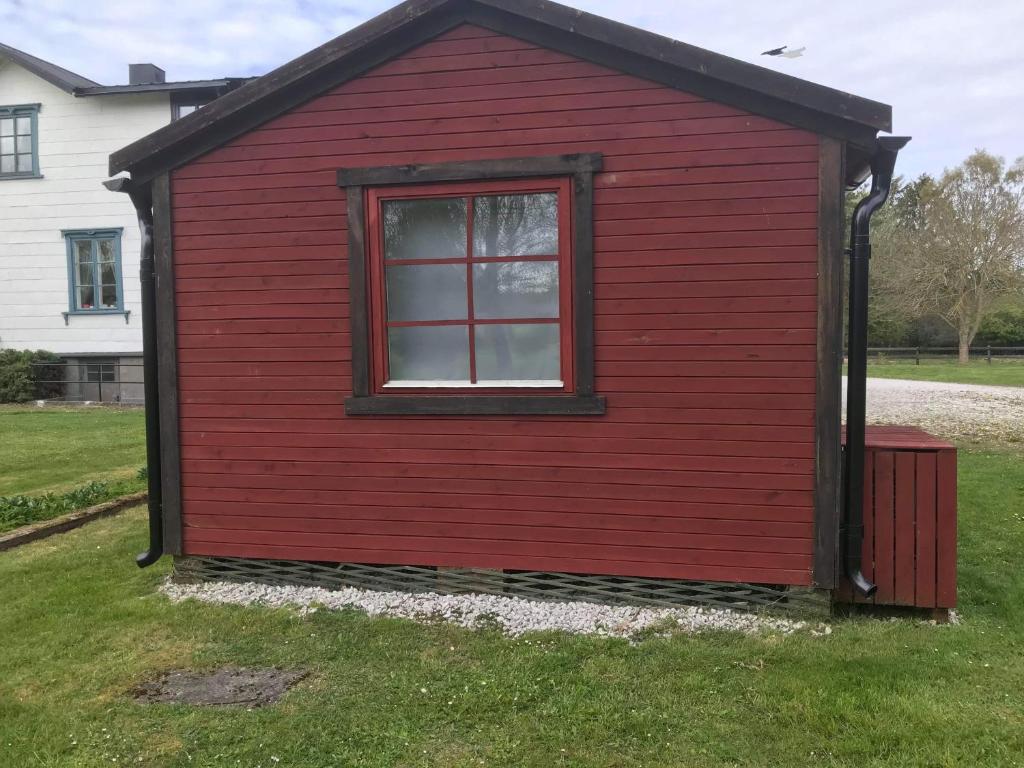 a red building with a window in the grass at Stuga in Romakloster