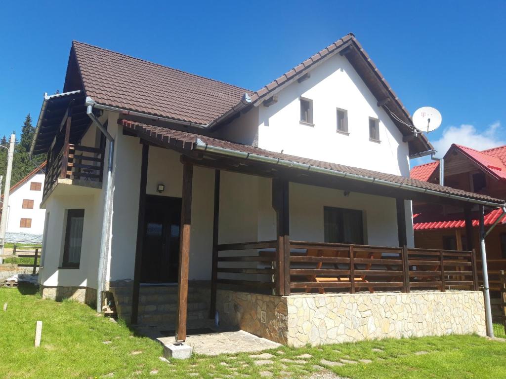 ein weißes Haus mit braunem Dach in der Unterkunft CABANA DORULUI in Tău Bistra