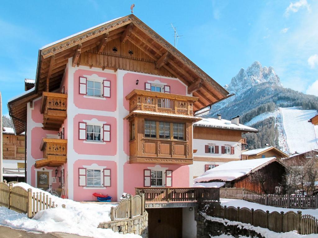 a pink house with a wooden roof in the snow at Apartment Brunel-1 by Interhome in Pozza di Fassa