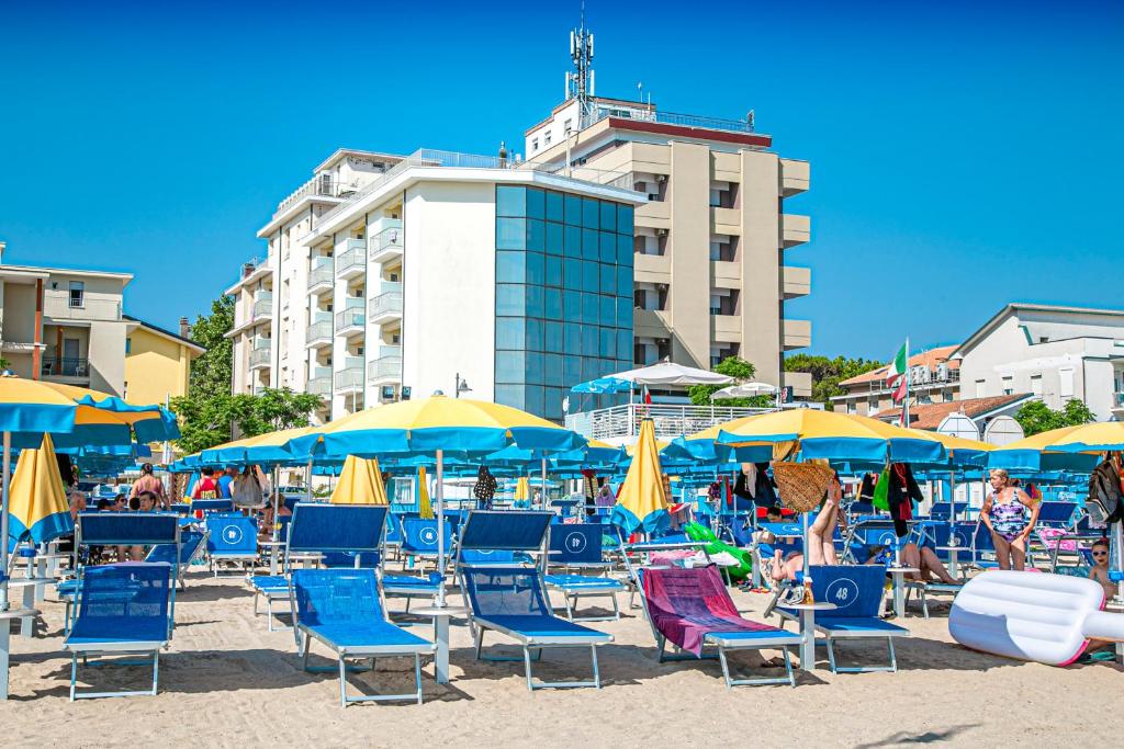 un mucchio di sedie e ombrelloni su una spiaggia di Hotel Ambasciatori a Bellaria-Igea Marina