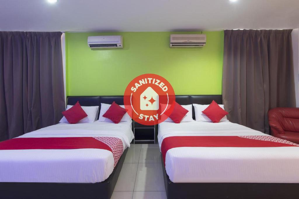 two beds in a room with green and red at OYO 44072 Mines Cempaka Hotel in Nilai