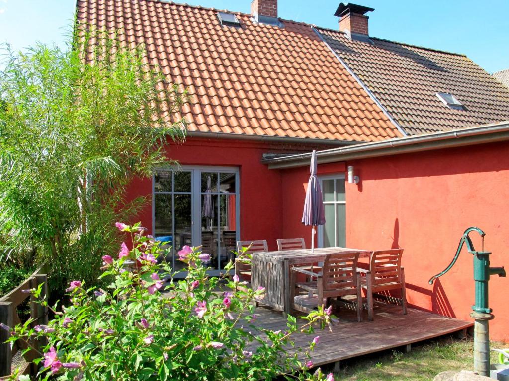 a red house with a wooden table and chairs at Holiday Home Kapitänshaus Leo by Interhome in Leopoldshagen