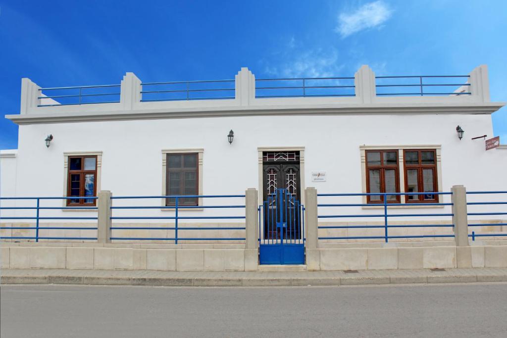 un edificio blanco con una puerta azul y una valla en A CASA DA VILA, en Almodôvar