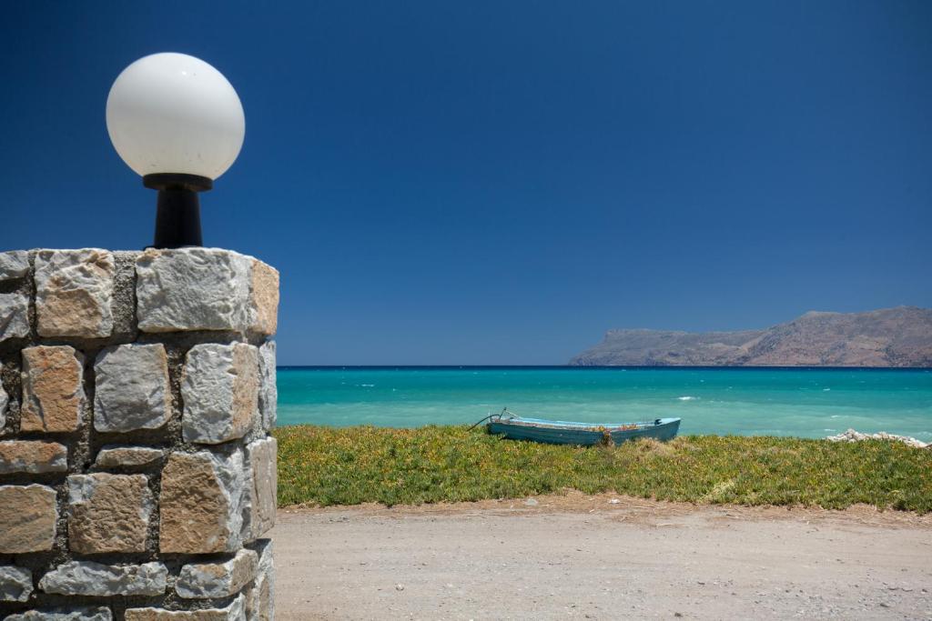 a light on a stone wall with a boat on the beach at Vasso Apartments 3 in Kissamos