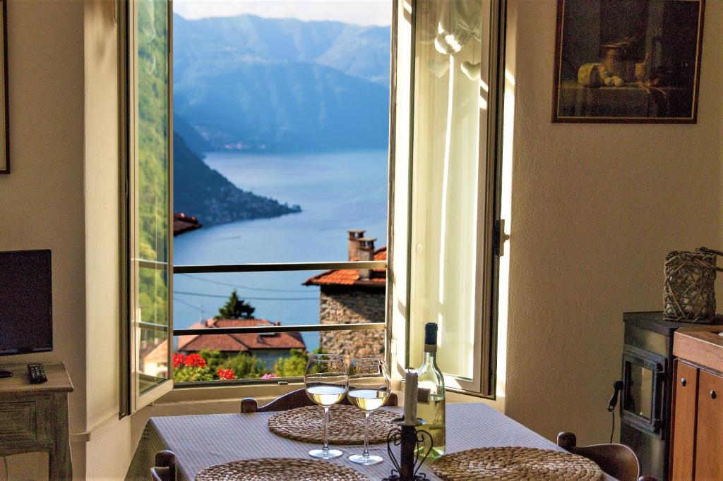 a table with wine glasses in front of a large window at Holiday Home Liliana in Faggeto Lario 