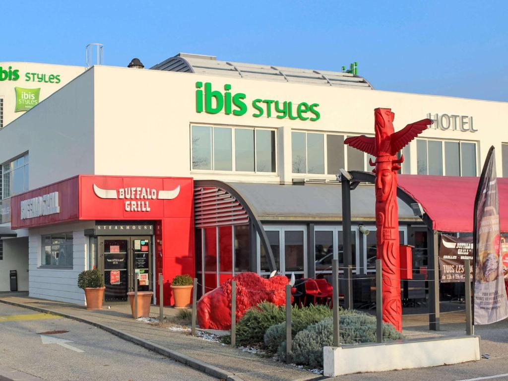 a building with a large red cross in front of it at Ibis Styles Crolles Grenoble A41 in Crolles