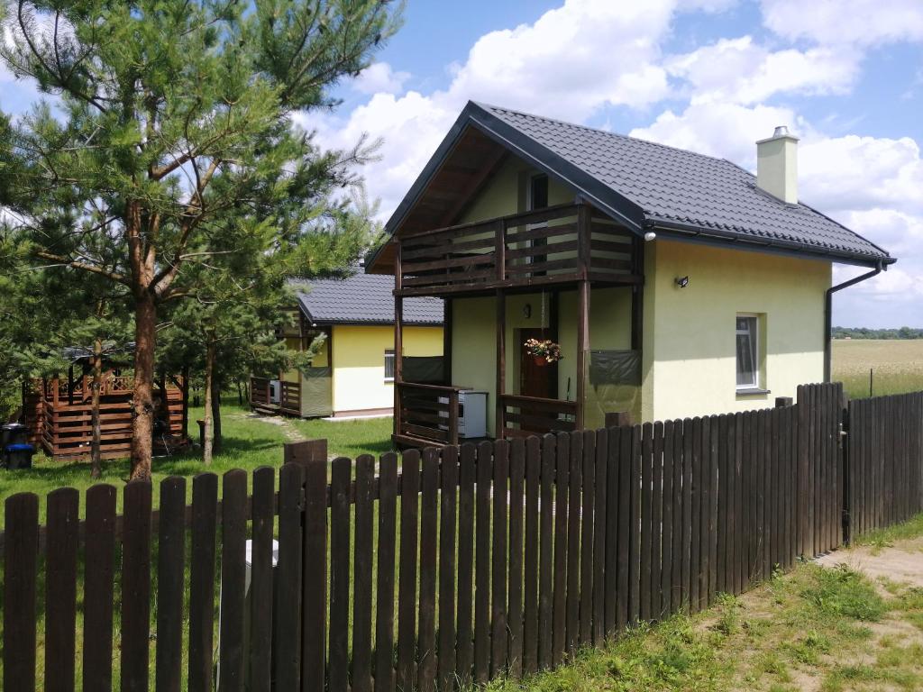 a house with a fence in front of it at Domki nad jeziorem in Dąbrówno