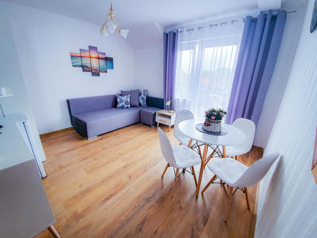 a living room with a table and chairs and a couch at Villa Róża pokoje & apartamenty in Łeba