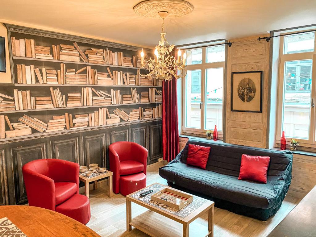 een woonkamer met een bank, stoelen en boekenplanken bij Les gites de Marie in Boulogne-sur-Mer