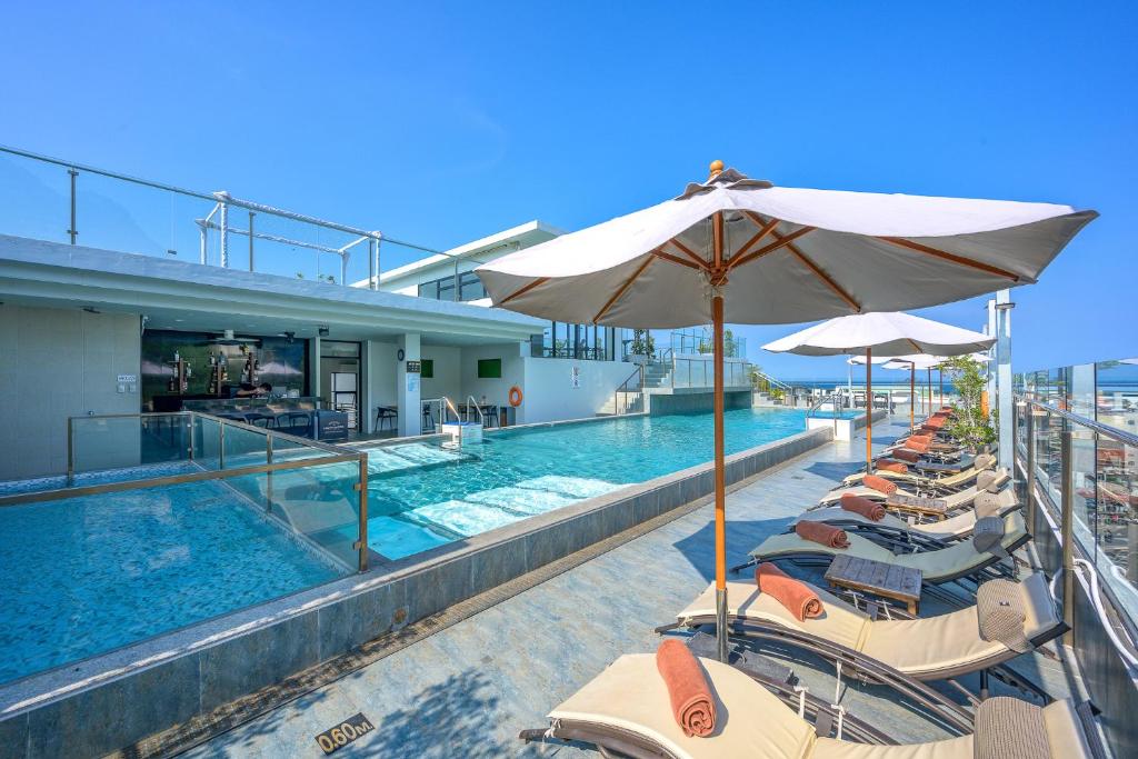 einen Pool mit Stühlen und Sonnenschirmen neben einem Gebäude in der Unterkunft Zenseana Resort & Spa - SHA Plus in Patong Beach