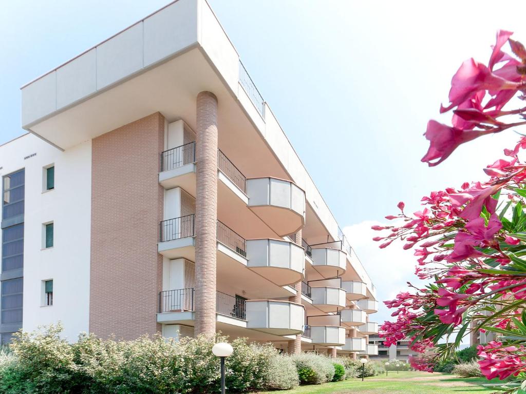 un edificio de apartamentos alto con flores rosas delante en Apartment Superior-4 by Interhome en San Vincenzo