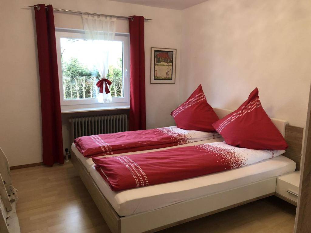 a bed with red pillows in a room with a window at SCHWARZWALDHIRSCH in Unterkirnach
