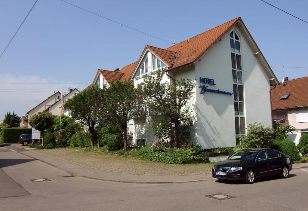 ein schwarzes Auto, das vor einem Haus parkt in der Unterkunft Hotel Zimmermann in Filderstadt