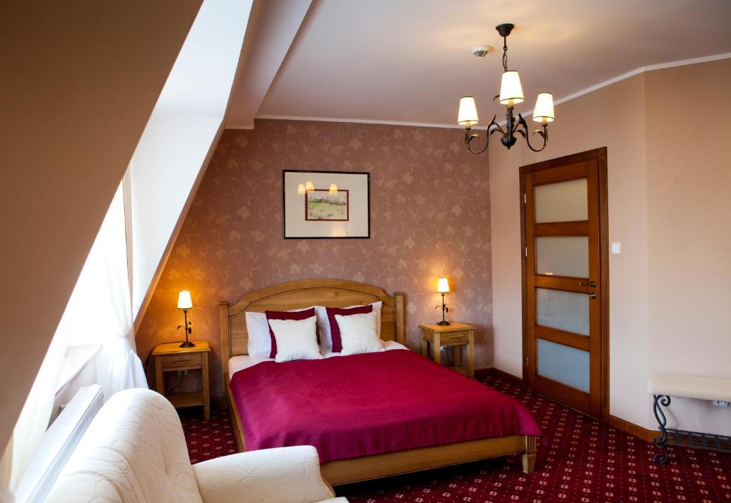 a bedroom with a bed with a red bedspread at Hotel i Restauracja "Pod Orłem" in Kartuzy