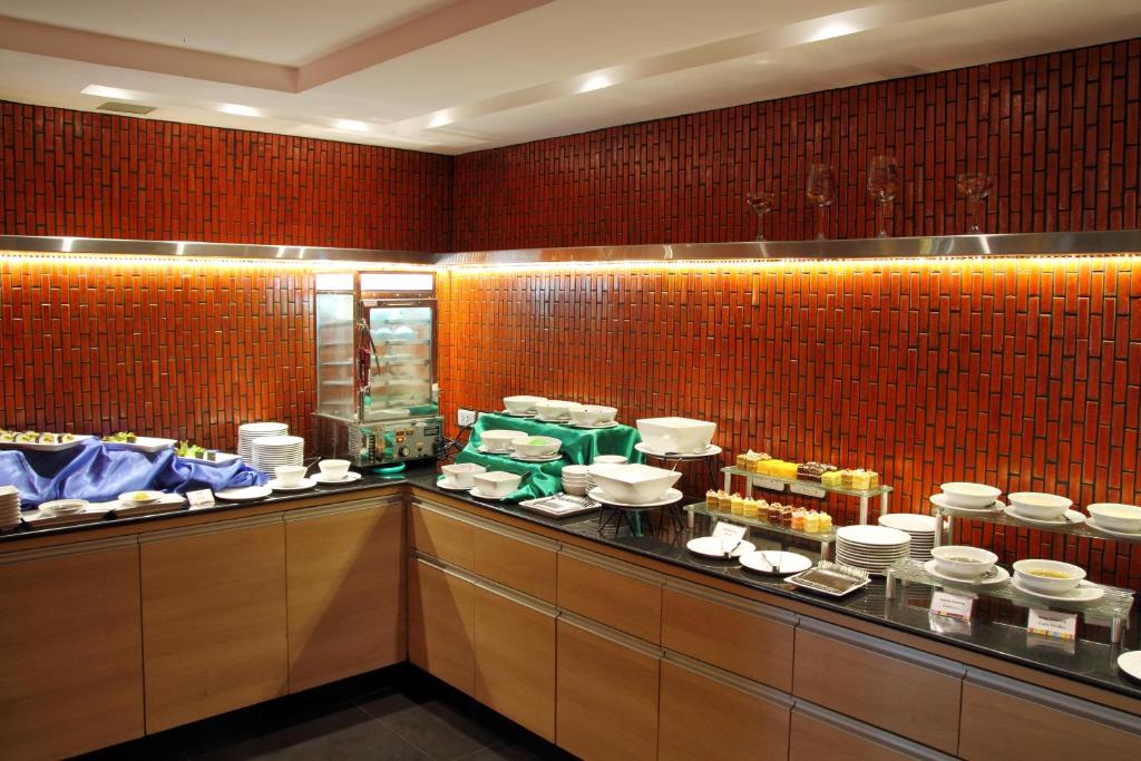 A restaurant counter displays plated breakfast items, pastries, fruit, and serving ware.