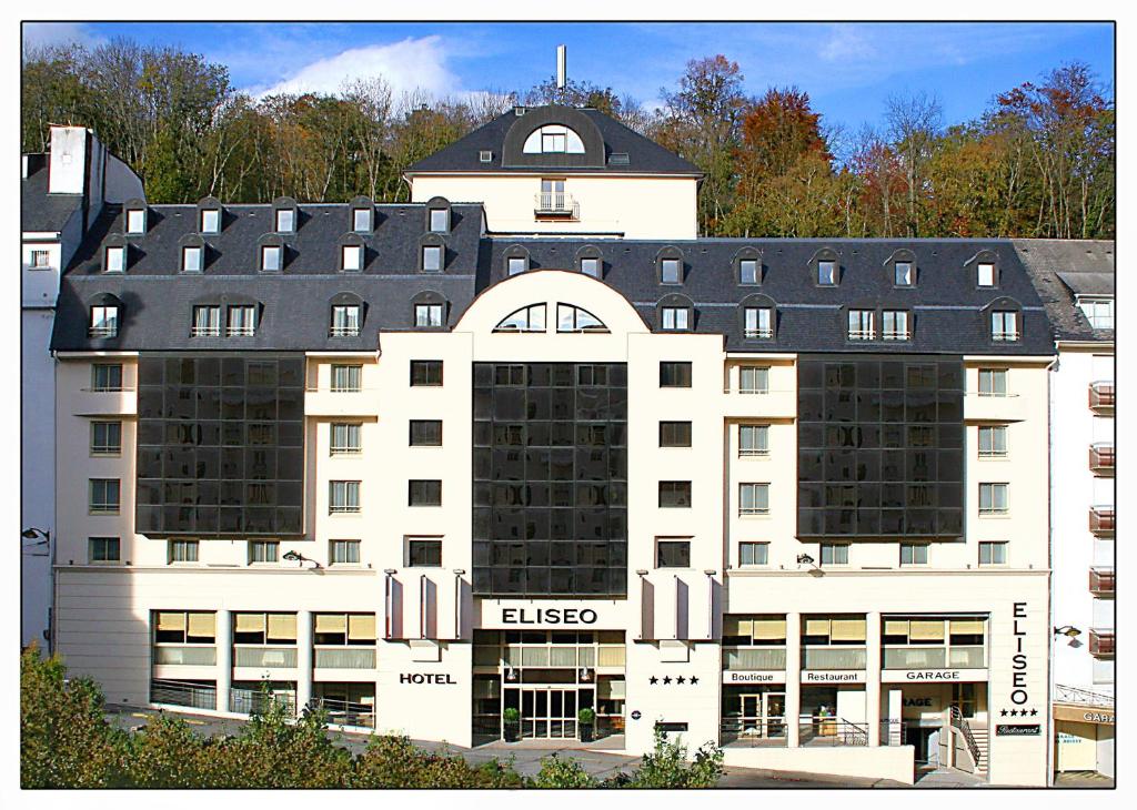 um grande edifício branco com um telhado preto em Hôtel Eliseo em Lourdes