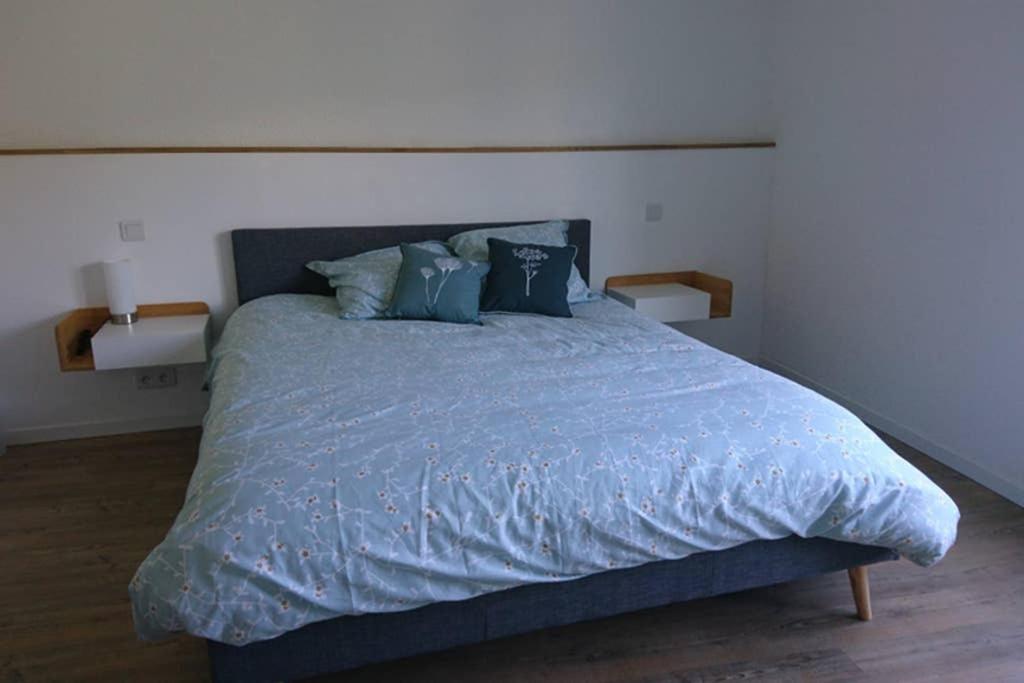 1 dormitorio con 1 cama con sábanas y almohadas azules en Gîte de charme en Ardèche : vue panoramique, plage privée en Saint-Fortunat-sur-Eyrieux