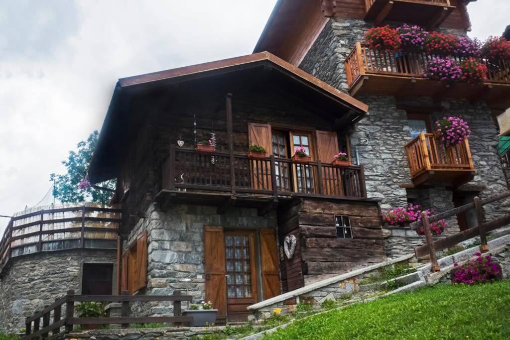 una casa de piedra con balcones y flores. en Chalet indipendente in centro a Valtournenche, en Valtournenche