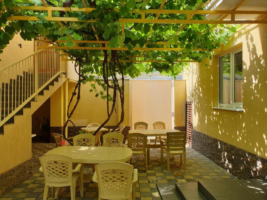 a patio with tables and chairs in a building at Guest House Vinogradnaya 4 in Anapa