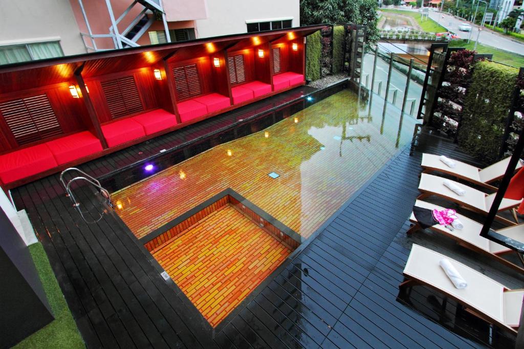 An elevated view of the illuminated pool deck with red cabana seating and loungers.