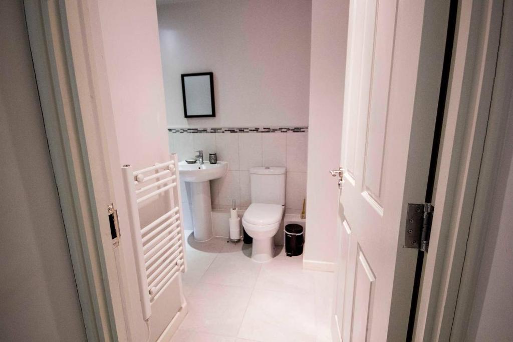 a white bathroom with a toilet and a sink at StayZo Modern Studio Apartment 1 in Bradford City in Bradford
