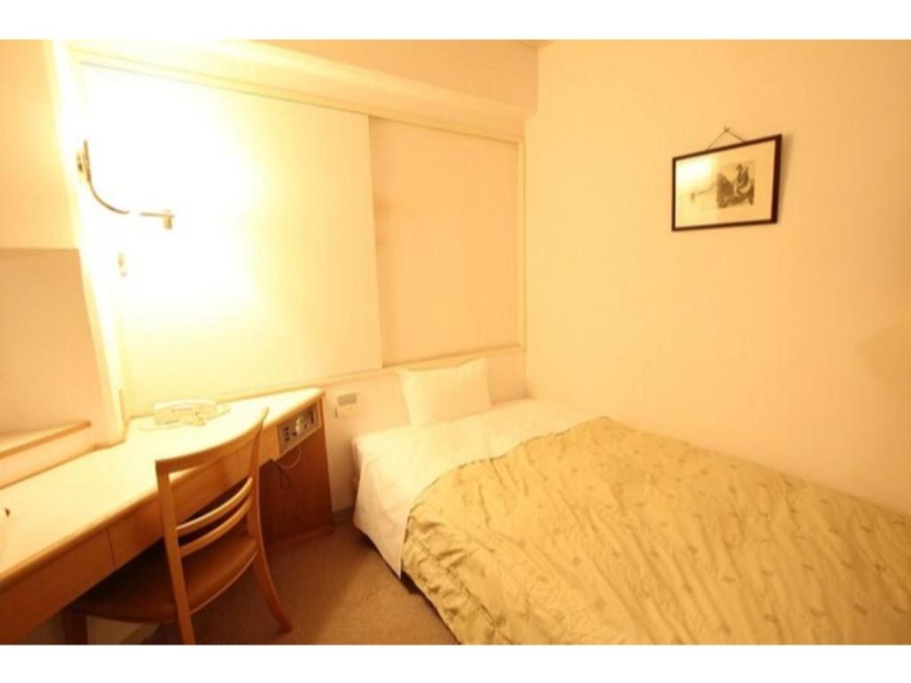 um pequeno quarto com uma cama, uma secretária e uma janela em Mizusawa Ground Hotel - Vacation STAY 84949 em Oshu