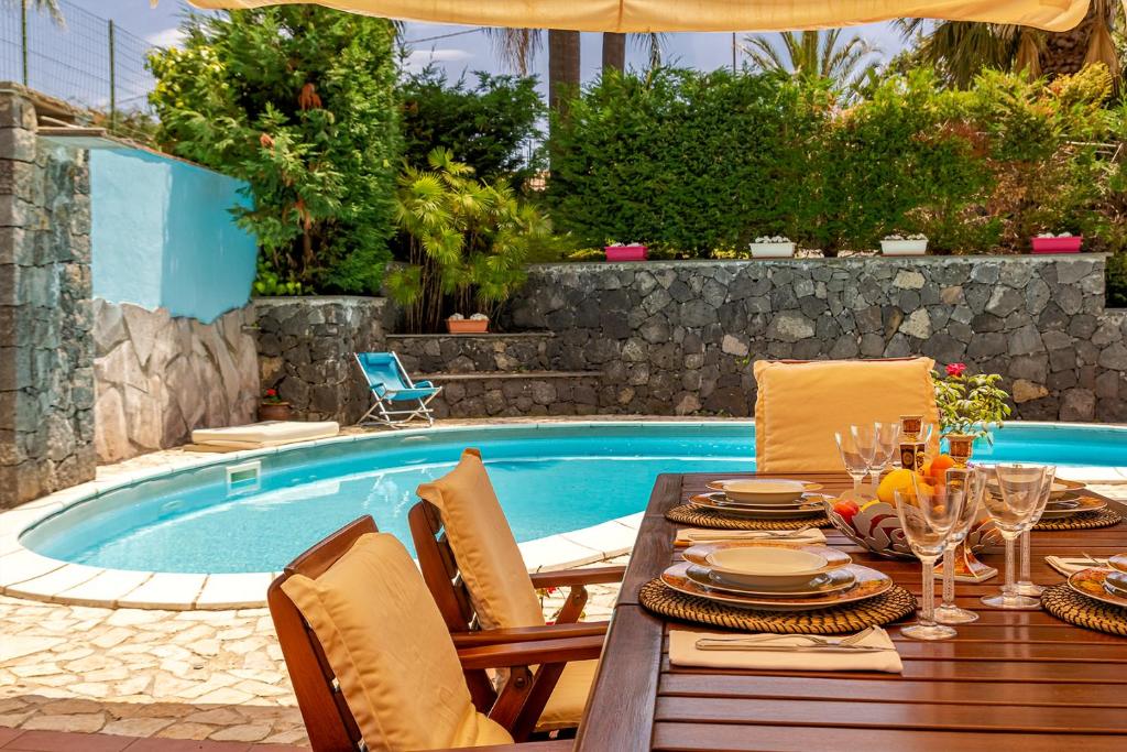 uma mesa de jantar e cadeiras ao lado de uma piscina em Villa Magdalena em Aci SantʼAntonio