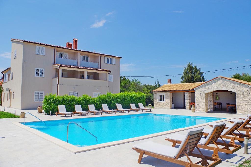 a villa with a swimming pool and a house at Holiday apartments in house Sanja in Rakalj