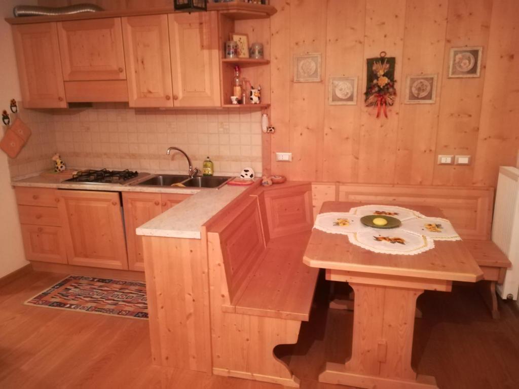 uma cozinha com armários de madeira, um lavatório e uma mesa em App. Frassino em Sappada