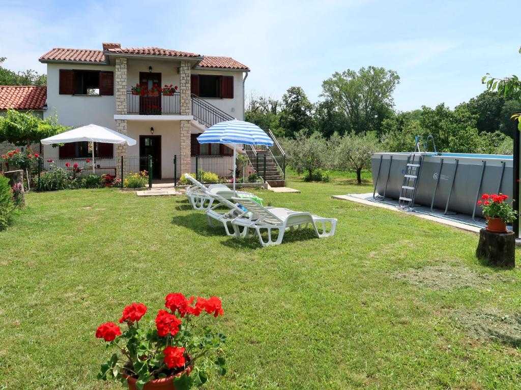a yard with two chairs and an umbrella and a house at Holiday Home Fortica - LBN330 by Interhome in Nedeščina