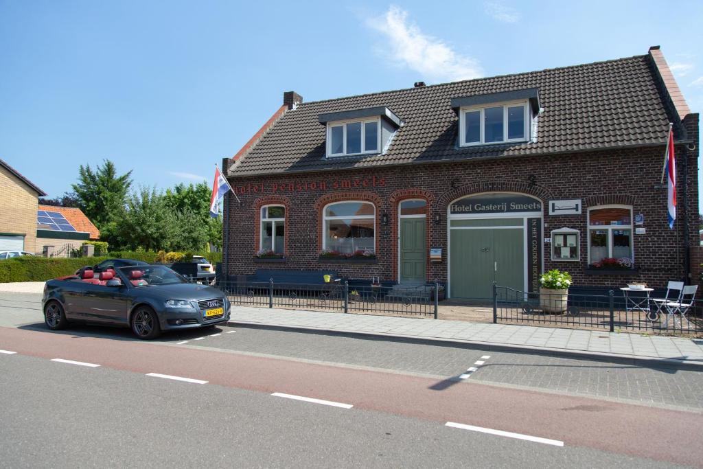 een auto geparkeerd voor een bakstenen gebouw bij Gastenverblijf 't Smedenhuys in Maasbracht