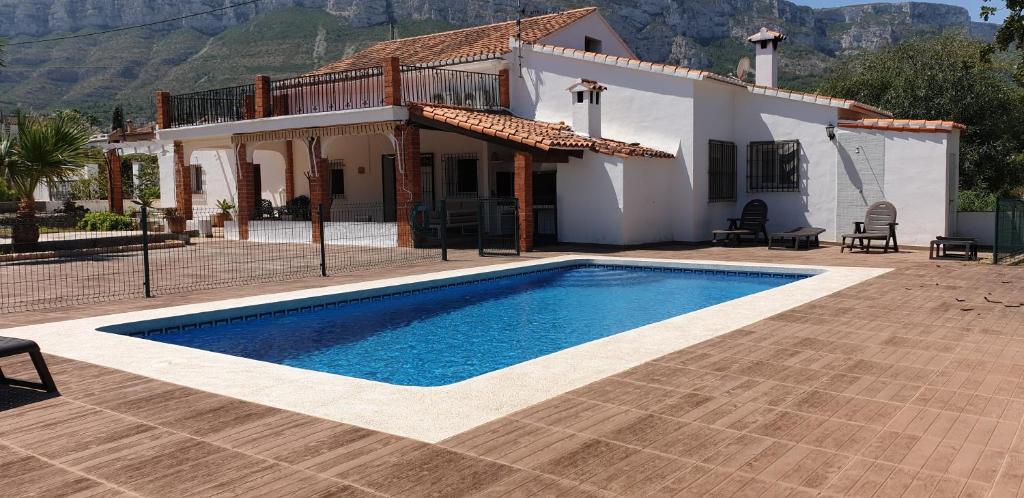 a villa with a swimming pool in front of a house at Chalet Cami de Merle in Denia