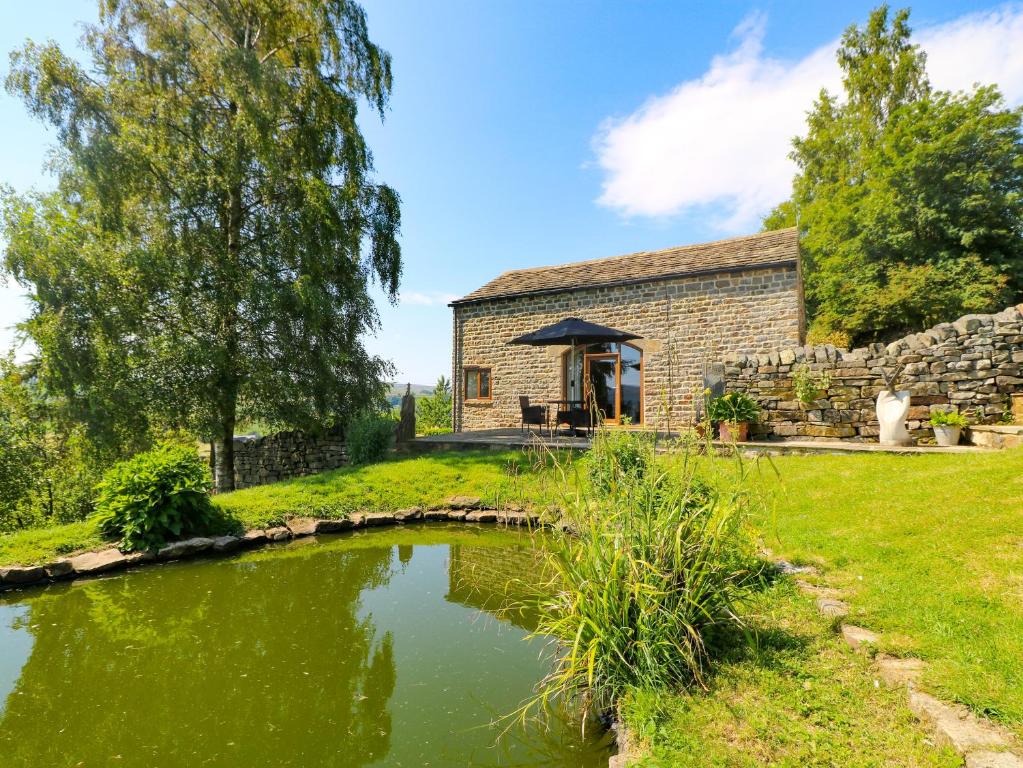 ein Cottage aus Stein mit einem Teich davor in der Unterkunft The Barn in Harrogate