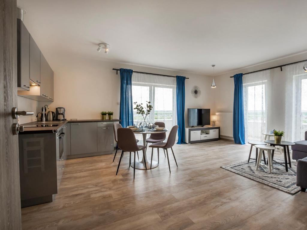 een keuken en een woonkamer met een tafel en stoelen bij VacationClub – 5 Mórz Sianożęty Apartament 1K,39 in Sianozety