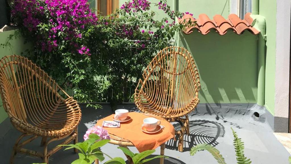 twee stoelen en een tafel op een patio met bloemen bij Welcomely - Casa Vacanze Zarinu in Orgosolo