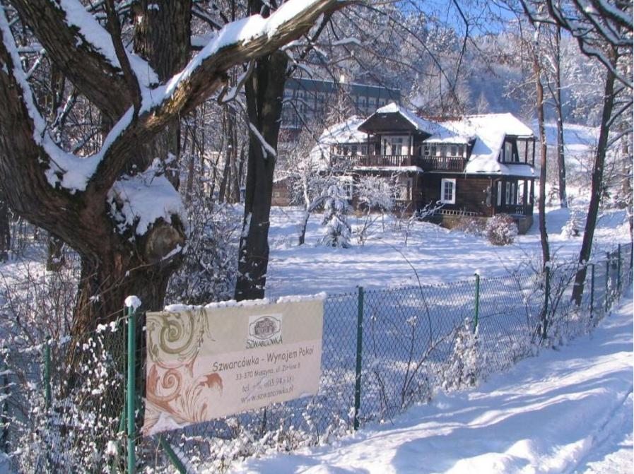 a sign in front of a house in the snow at Szwarcówka in Muszyna