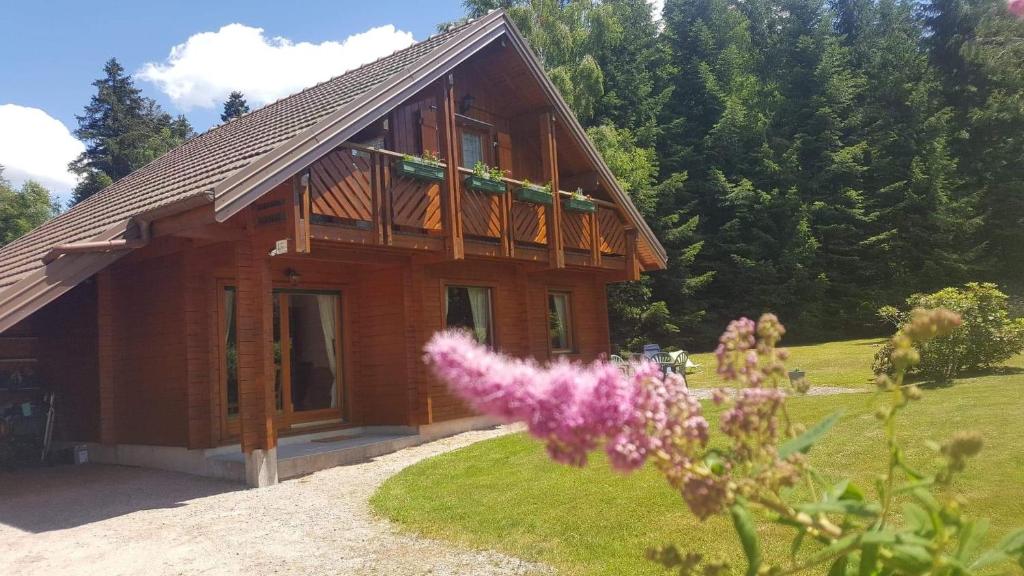 a log cabin with a porch and flowers in front of it at Chalet cosy & confort Spa,Sauna,Pétanque,VE - Top situation à Gérardmer in Gérardmer
