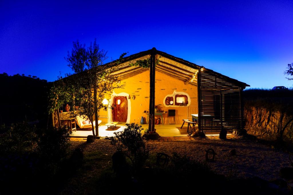 a small house with a lit up yard at night at The Hobbit House - Montes da Ronha in Odemira