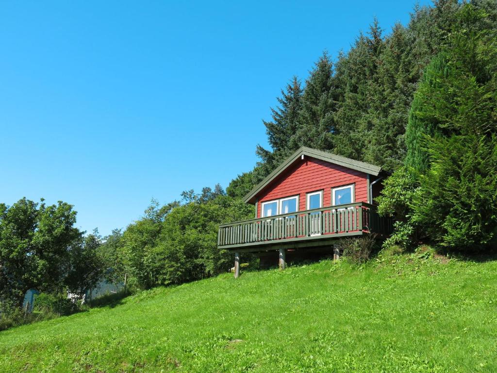 ein rotes Haus auf einem Grashügel in der Unterkunft Holiday Home Oasen - FJS143 by Interhome in Sørbø