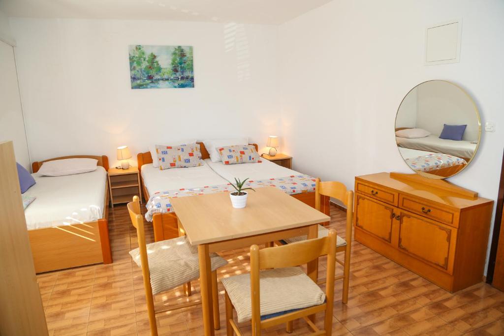 Habitación con 2 camas, mesa y espejo. en Apartments Butkovic en Hvar