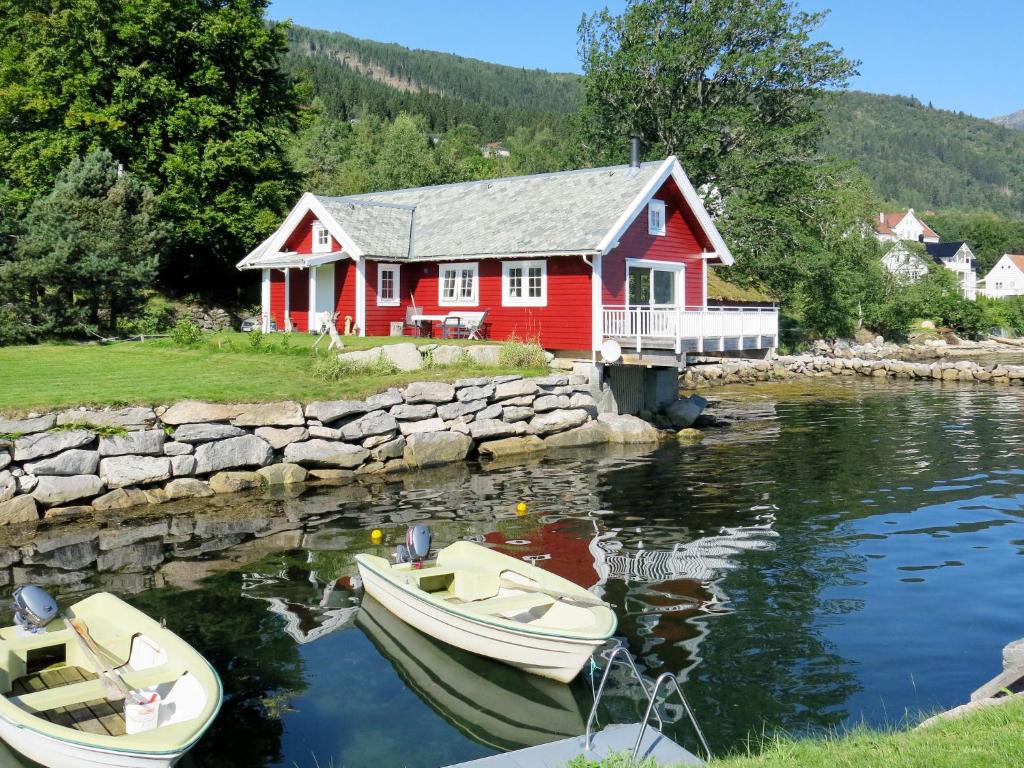una casa roja con dos barcos en el agua en Chalet Naustet - FJS027, en Balestrand