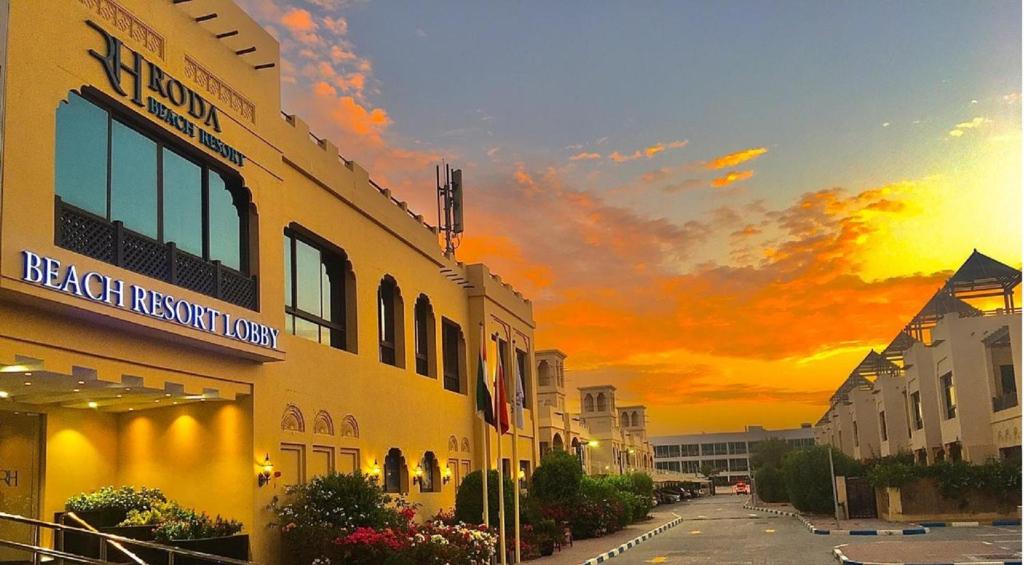 a yellow building with a sunset in the background at Roda Beach Resort in Dubai