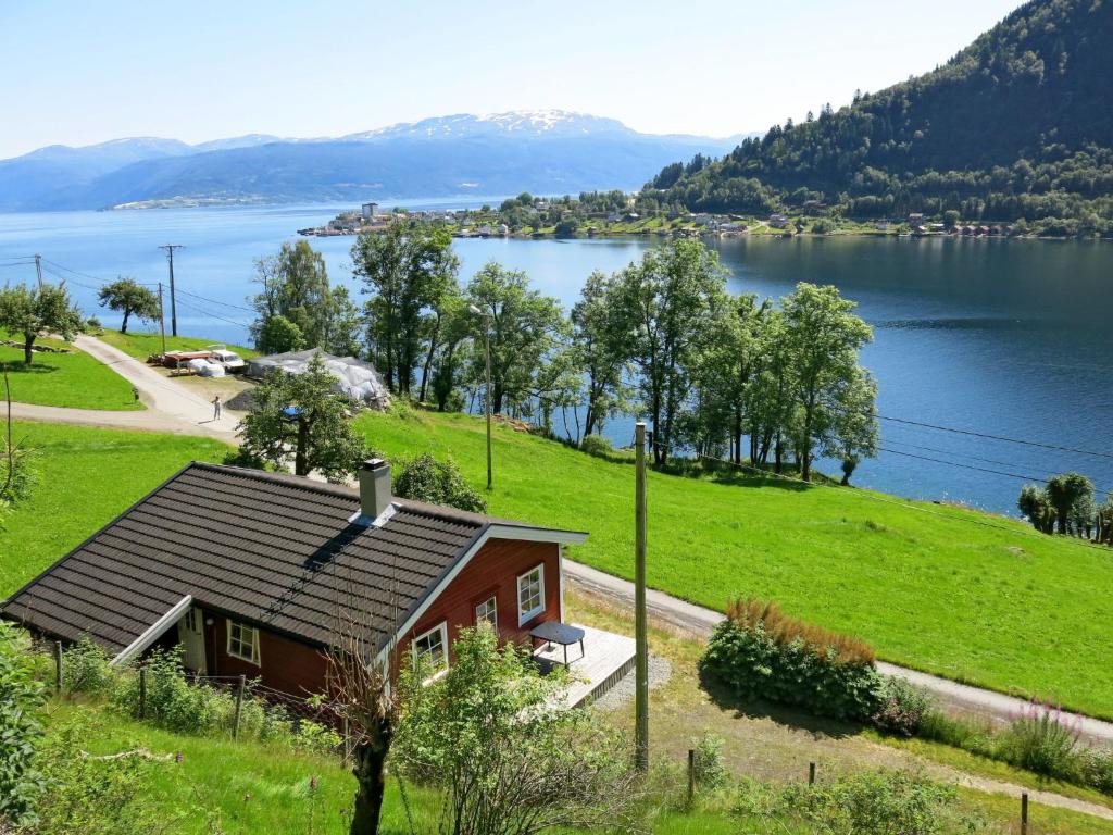 a small house on a hill next to a lake at Holiday Home Pærehagen - FJS297 by Interhome in Balestrand