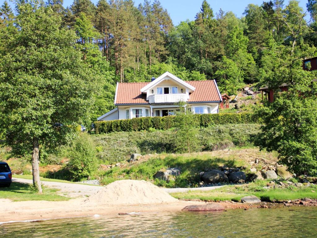 ein Haus auf einem Hügel neben einem Wasserkörper in der Unterkunft Holiday Home Naudøyna - SOW046 by Interhome in Lyngdal